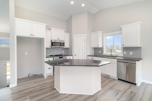 kitchen featuring stainless steel appliances, a kitchen island, white cabinets, and light wood-style flooring