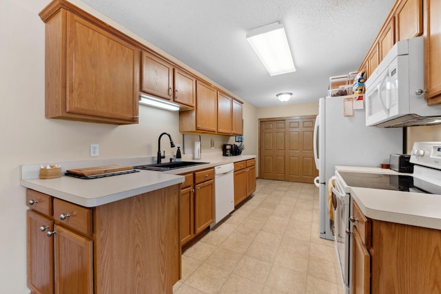 kitchen featuring white appliances, brown cabinetry, light floors, and a sink