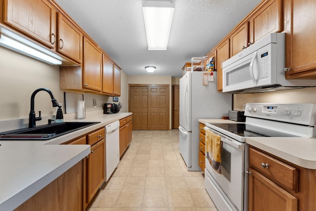 kitchen with a sink, white appliances, brown cabinetry, and light countertops