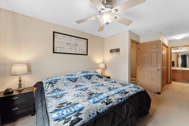 bedroom with a ceiling fan, light colored carpet, and ensuite bathroom