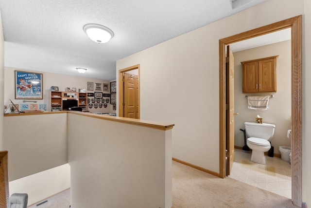 hall featuring baseboards, light carpet, a textured ceiling, and an upstairs landing