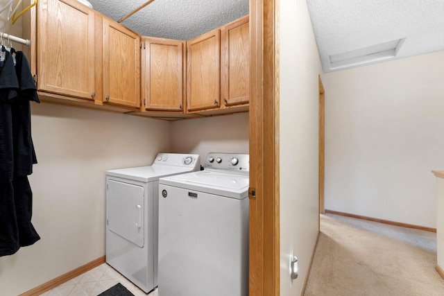 clothes washing area with washing machine and clothes dryer, baseboards, attic access, cabinet space, and a textured ceiling