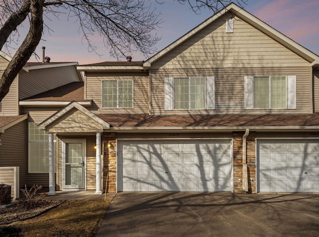 view of front of home with aphalt driveway, stone siding, and an attached garage