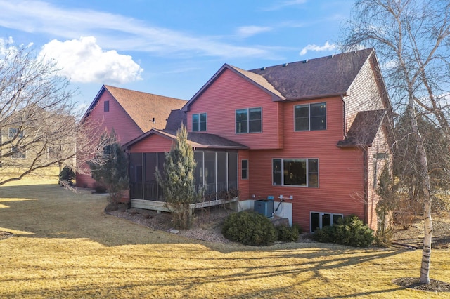 rear view of house with cooling unit, a lawn, roof with shingles, and a sunroom