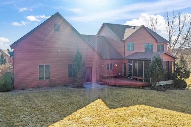 rear view of house with a yard, a deck, and a sunroom