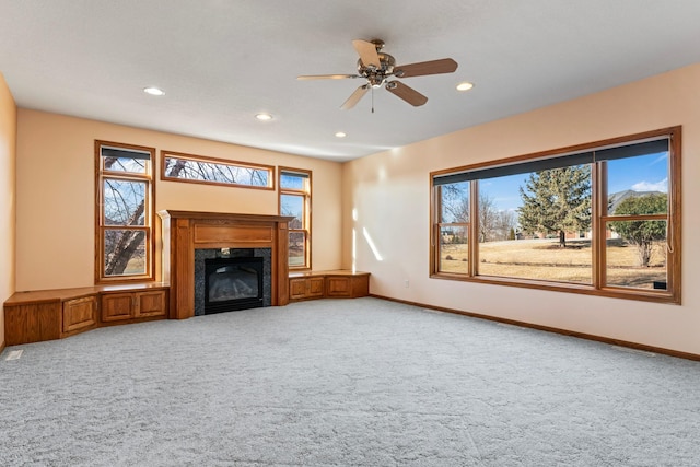 unfurnished living room featuring a premium fireplace, carpet floors, plenty of natural light, and baseboards