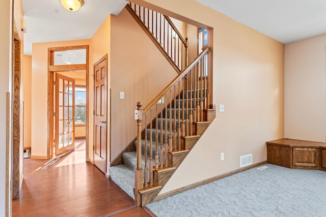 stairs featuring visible vents, baseboards, and wood finished floors