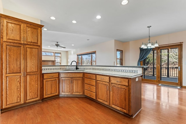 kitchen featuring brown cabinetry, light wood-style flooring, light countertops, and a sink