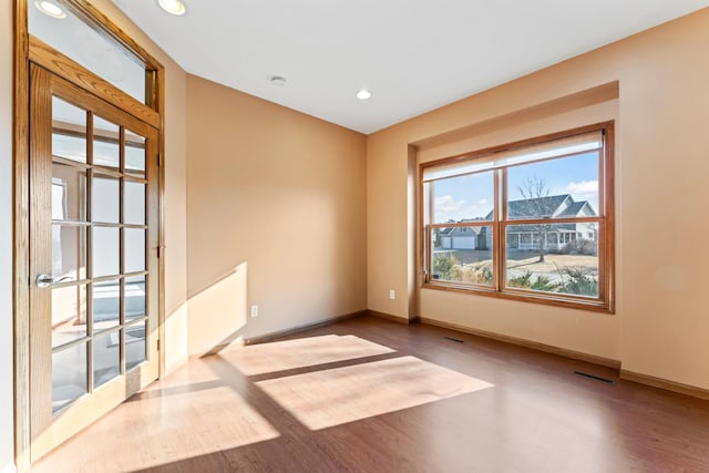 spare room featuring recessed lighting, baseboards, and wood finished floors