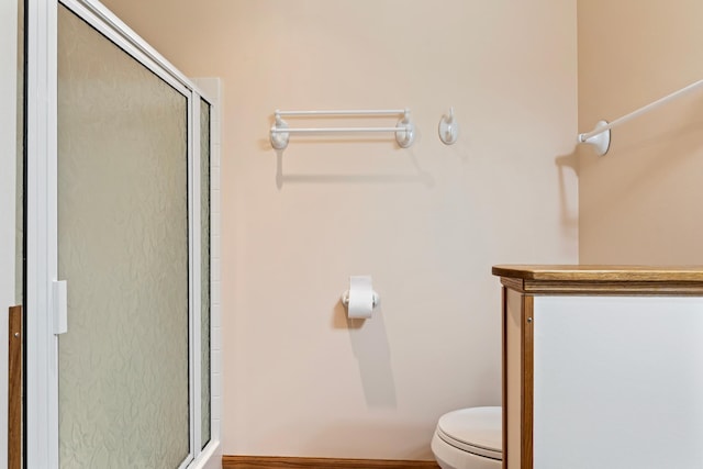 bathroom featuring a shower with shower door and toilet