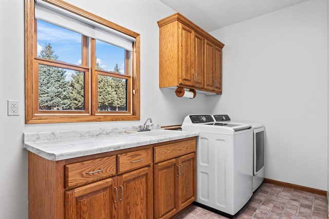 laundry area with a sink, baseboards, cabinet space, and separate washer and dryer