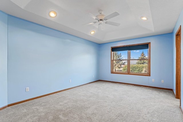 carpeted spare room featuring visible vents, a ceiling fan, a tray ceiling, recessed lighting, and baseboards