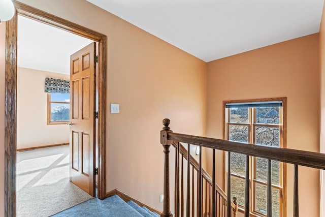 hall with baseboards, an upstairs landing, and carpet