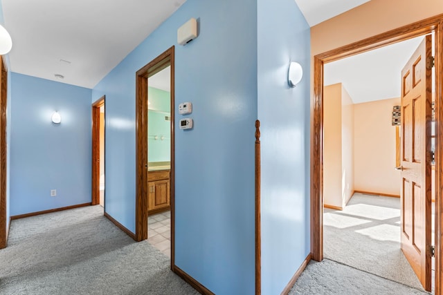 corridor featuring light carpet and baseboards