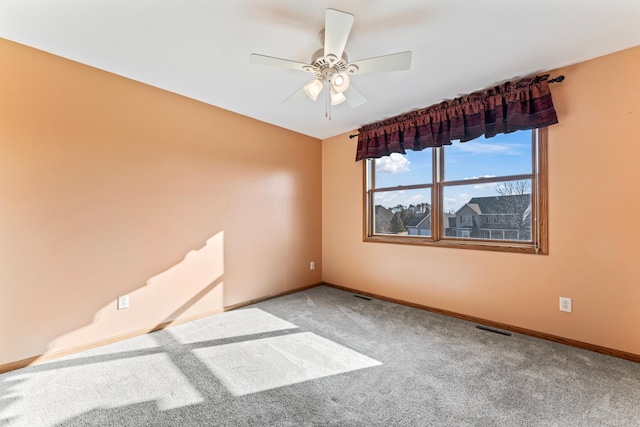 carpeted spare room featuring visible vents, baseboards, and ceiling fan