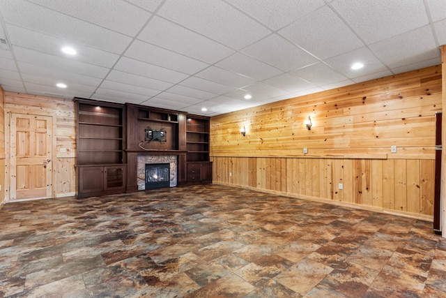 unfurnished living room with wooden walls, recessed lighting, a fireplace, and baseboards