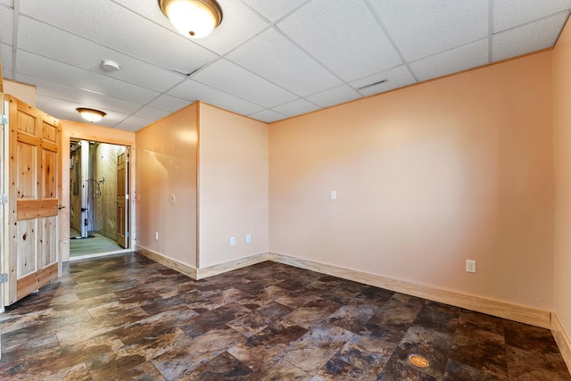 unfurnished room featuring visible vents, stone finish floor, a paneled ceiling, and baseboards