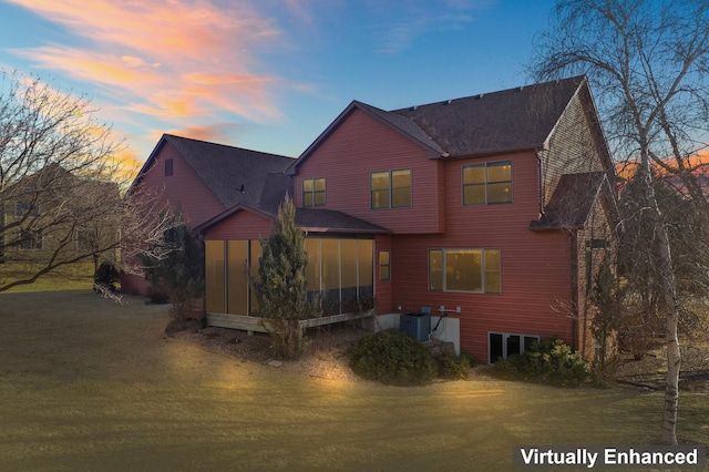 rear view of house featuring a lawn, cooling unit, and a sunroom