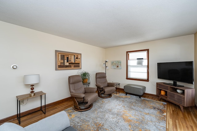 sitting room with wood finished floors, baseboards, and a textured ceiling