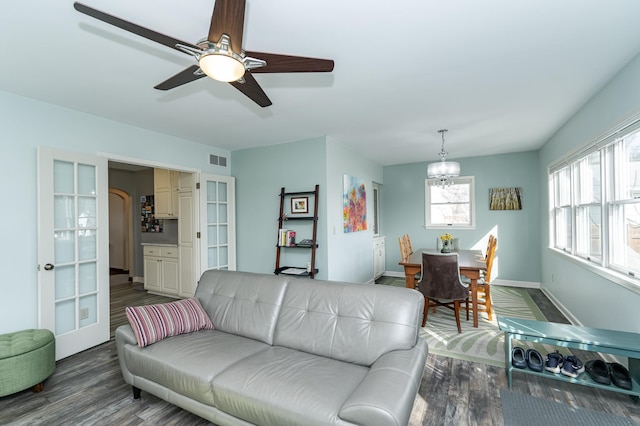 living room featuring visible vents, an inviting chandelier, baseboards, and wood finished floors