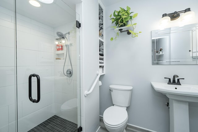 bathroom with a stall shower, toilet, and a sink