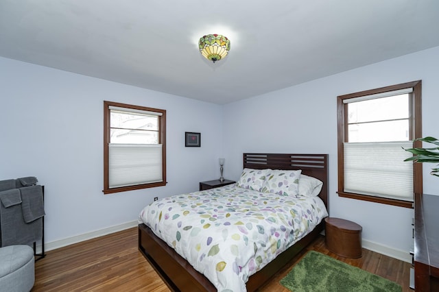 bedroom with multiple windows, baseboards, and wood finished floors