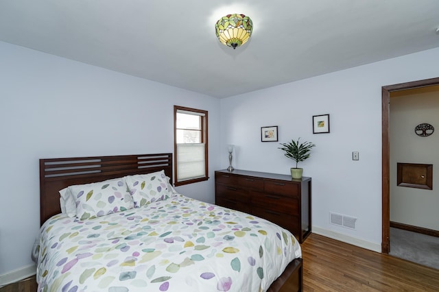 bedroom with visible vents, baseboards, and wood finished floors