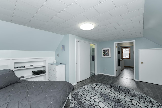 unfurnished bedroom featuring baseboards, dark wood-type flooring, and lofted ceiling