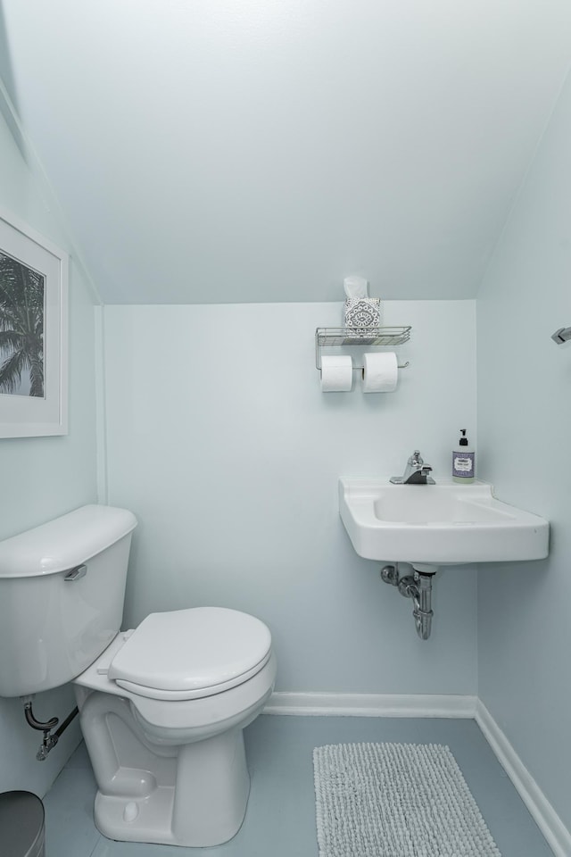 bathroom featuring a sink, baseboards, lofted ceiling, and toilet