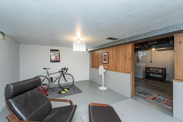 sitting room with finished concrete floors, washer / clothes dryer, concrete block wall, and visible vents