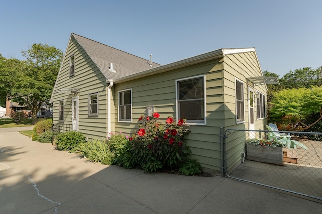 view of side of property featuring a shingled roof and fence