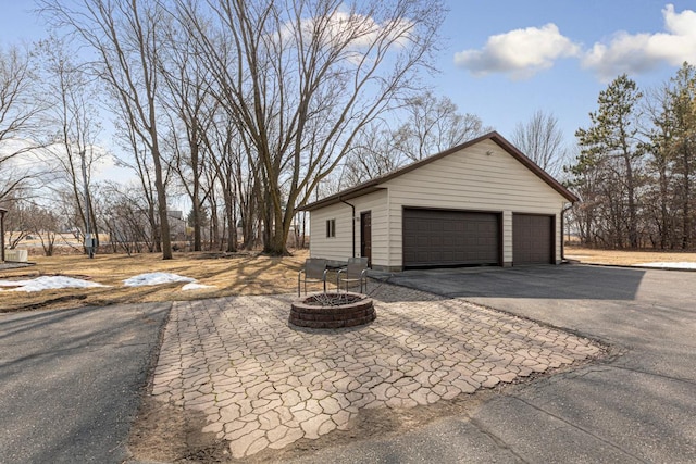 view of home's exterior featuring a garage, an outbuilding, and an outdoor fire pit