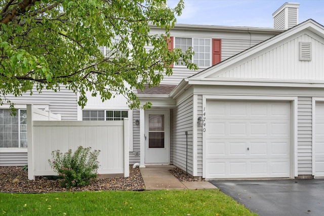 view of front of house with a garage, fence, a shingled roof, and aphalt driveway