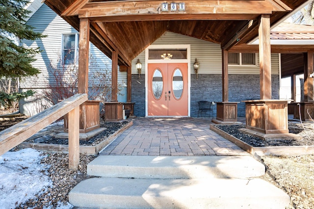 doorway to property with stone siding and metal roof