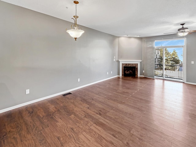 unfurnished living room featuring a premium fireplace, baseboards, and wood finished floors