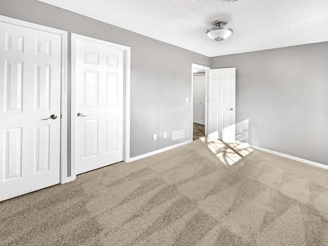 unfurnished bedroom featuring baseboards, carpet floors, a textured ceiling, and visible vents