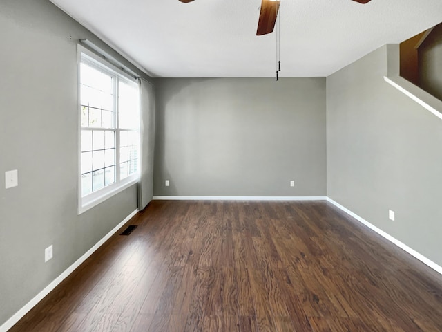 empty room featuring dark wood finished floors, baseboards, visible vents, and ceiling fan