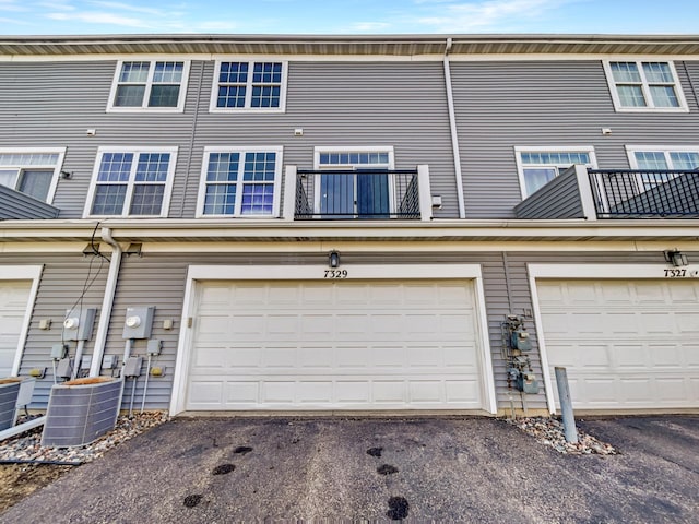 rear view of property with aphalt driveway, a balcony, and central AC