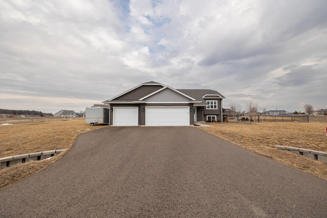 view of front facade with aphalt driveway, an attached garage, and fence