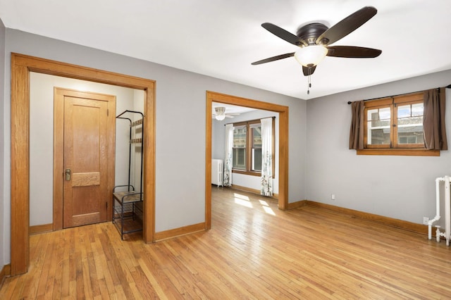 empty room with light wood-style flooring, radiator, and ceiling fan