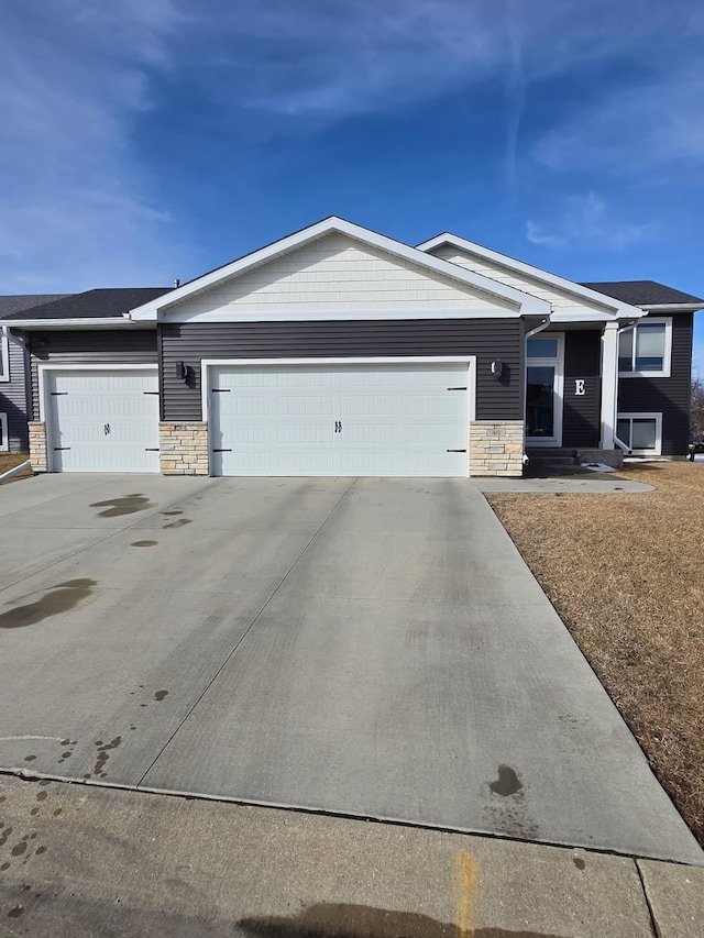 ranch-style house with stone siding, an attached garage, and concrete driveway