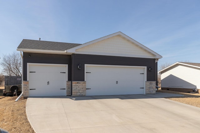 view of front of home featuring stone siding, driveway, a garage, and fence