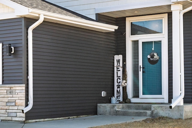 property entrance featuring stone siding and roof with shingles