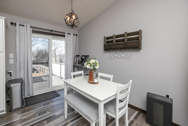 dining space featuring lofted ceiling, wood finished floors, baseboards, and a chandelier