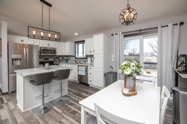 kitchen with backsplash, a center island, appliances with stainless steel finishes, white cabinets, and dark wood-style flooring