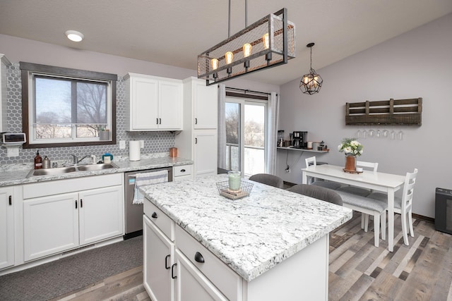 kitchen with backsplash, dishwasher, lofted ceiling, light wood-style flooring, and a sink