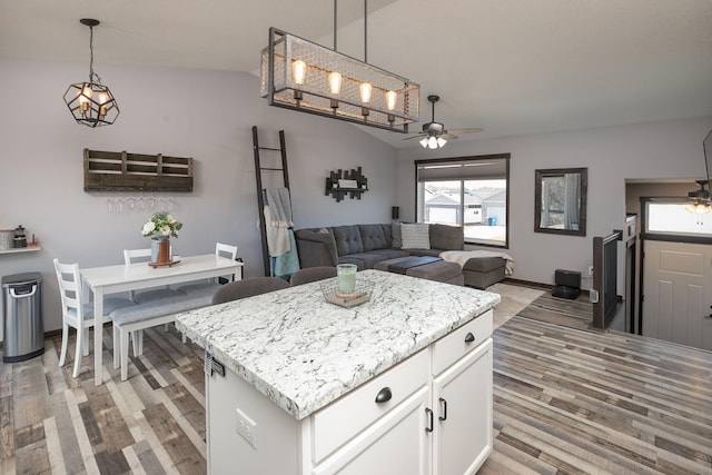 kitchen with hanging light fixtures, white cabinetry, light wood-type flooring, and a ceiling fan