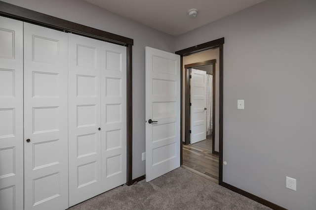 unfurnished bedroom featuring a closet, baseboards, and carpet floors