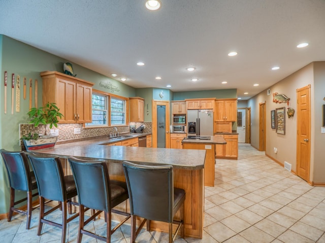 kitchen with a kitchen breakfast bar, backsplash, a center island, appliances with stainless steel finishes, and a peninsula