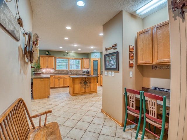 kitchen with light tile patterned flooring, recessed lighting, a textured ceiling, and a center island